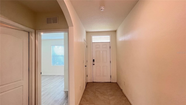 doorway to outside featuring light hardwood / wood-style flooring and a textured ceiling