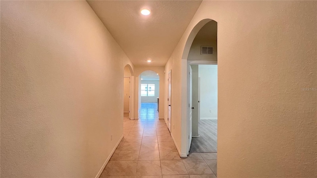 hall with a textured ceiling and light tile patterned floors