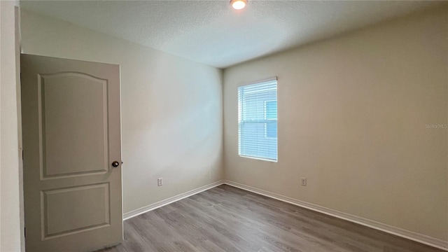 spare room featuring light hardwood / wood-style floors and a textured ceiling