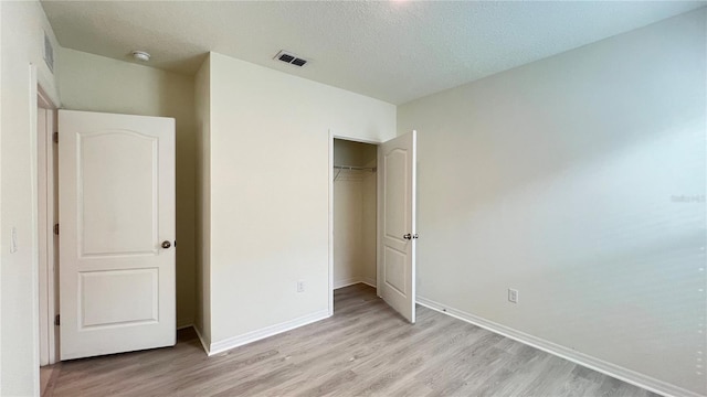 unfurnished bedroom with a closet, a textured ceiling, and light wood-type flooring