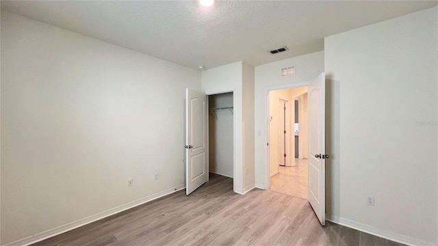 unfurnished bedroom featuring a closet, a textured ceiling, and light hardwood / wood-style floors