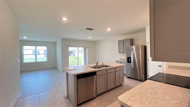 kitchen with a center island with sink, appliances with stainless steel finishes, a textured ceiling, gray cabinets, and sink