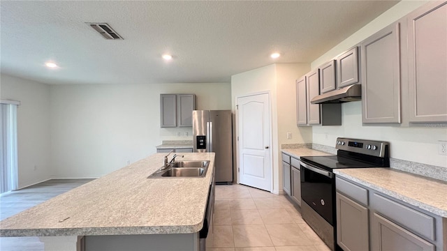 kitchen featuring appliances with stainless steel finishes, sink, a textured ceiling, gray cabinets, and a center island with sink