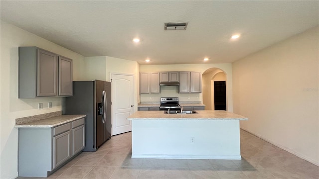 kitchen featuring an island with sink, gray cabinetry, stainless steel appliances, sink, and light tile patterned floors