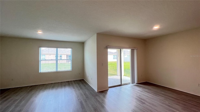 unfurnished room featuring a textured ceiling and dark hardwood / wood-style flooring