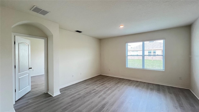 empty room with hardwood / wood-style flooring and a textured ceiling