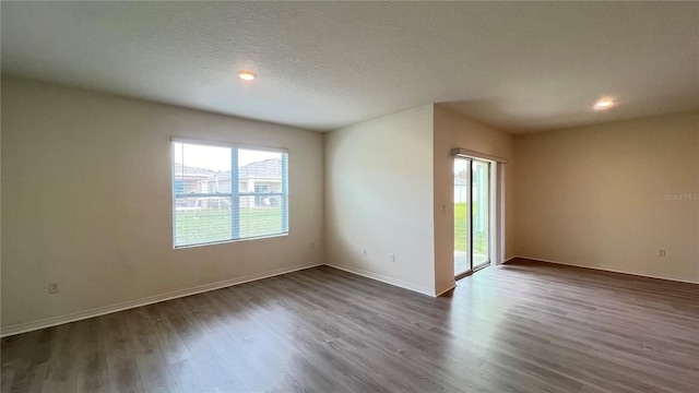 empty room featuring a textured ceiling and dark wood-type flooring