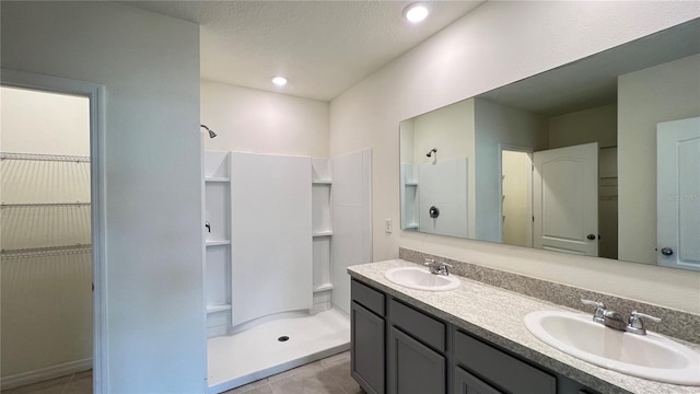 bathroom with vanity, a textured ceiling, a shower, and tile patterned flooring