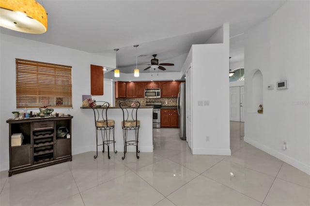 kitchen with lofted ceiling, a kitchen breakfast bar, decorative backsplash, kitchen peninsula, and stainless steel appliances