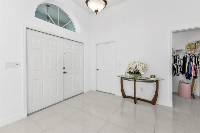 foyer entrance with light tile patterned flooring and high vaulted ceiling