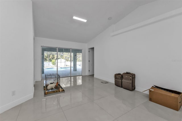 spare room featuring light tile patterned floors and lofted ceiling