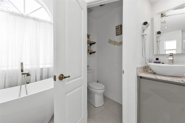 bathroom with a bathing tub, tile patterned flooring, vanity, and toilet