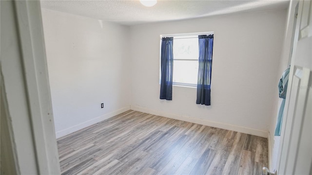 spare room with light hardwood / wood-style floors and a textured ceiling