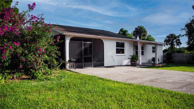 view of front of house with a sunroom, a front yard, and a patio area