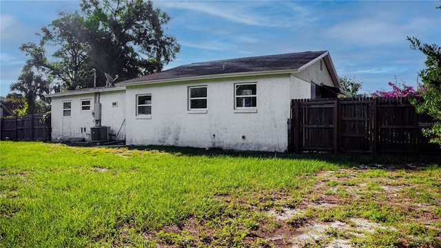 rear view of house with a yard and central AC