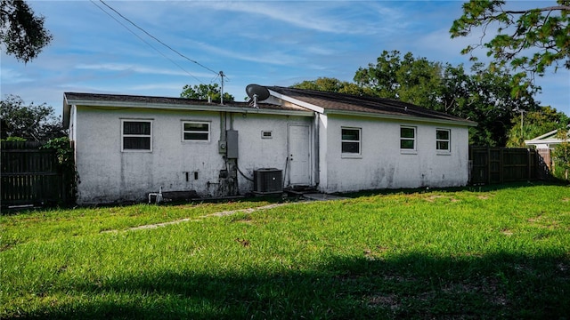 rear view of house featuring a yard and central AC unit