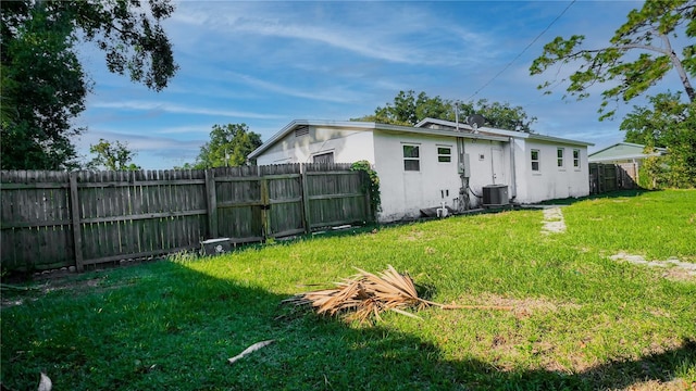 rear view of property with a yard and central AC unit