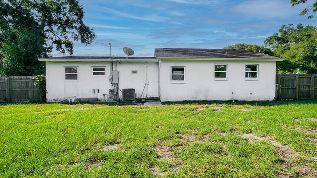 back of house with a lawn and central air condition unit