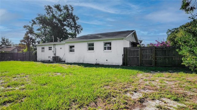 rear view of house featuring a yard and central AC