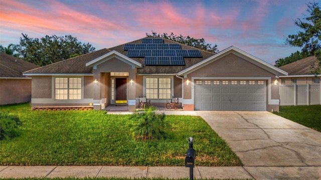 view of front facade featuring a garage, a yard, and solar panels