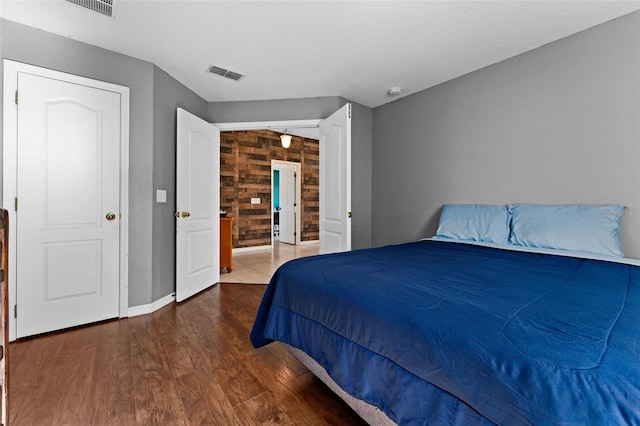 bedroom with wood walls and dark hardwood / wood-style flooring