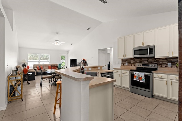 kitchen featuring light tile patterned flooring, sink, white cabinetry, stainless steel appliances, and a kitchen breakfast bar