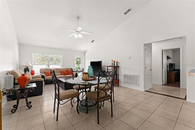 tiled dining room with ceiling fan and high vaulted ceiling