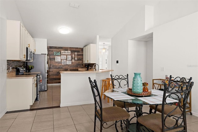 dining space with lofted ceiling, sink, and light tile patterned floors