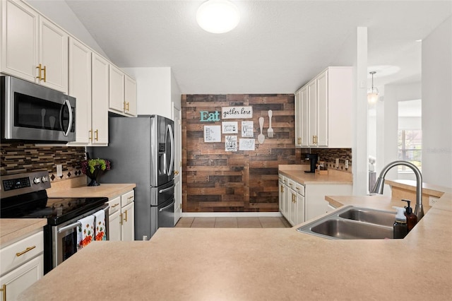 kitchen featuring white cabinets, sink, tasteful backsplash, wooden walls, and stainless steel appliances