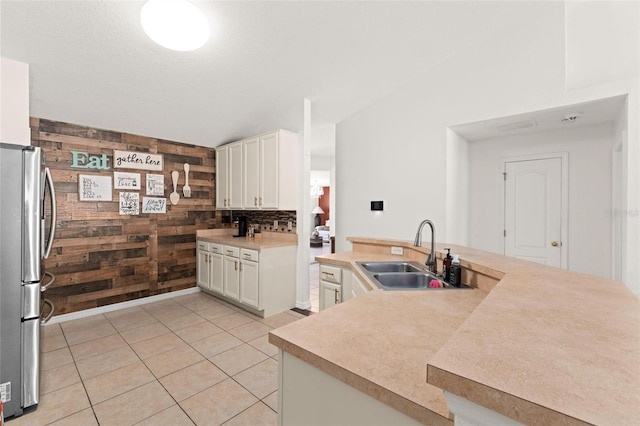 kitchen featuring wooden walls, decorative backsplash, stainless steel fridge, sink, and light tile patterned flooring