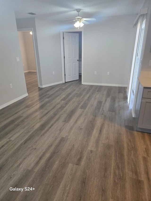 unfurnished living room with dark hardwood / wood-style flooring and ceiling fan