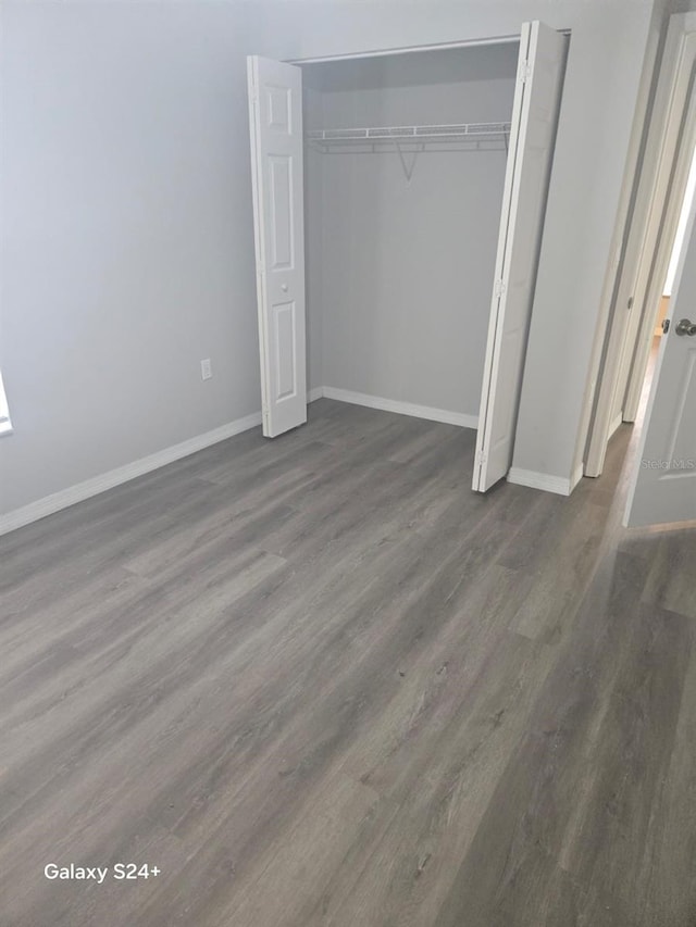 unfurnished bedroom with dark hardwood / wood-style flooring and a closet