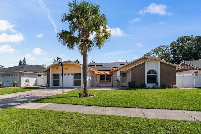 ranch-style home featuring a front yard, solar panels, and a garage