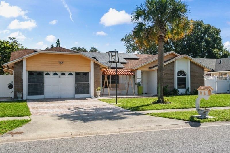 ranch-style house featuring solar panels, a front yard, and a garage