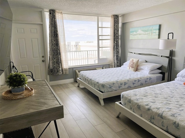 bedroom featuring a textured ceiling, multiple windows, and light hardwood / wood-style floors