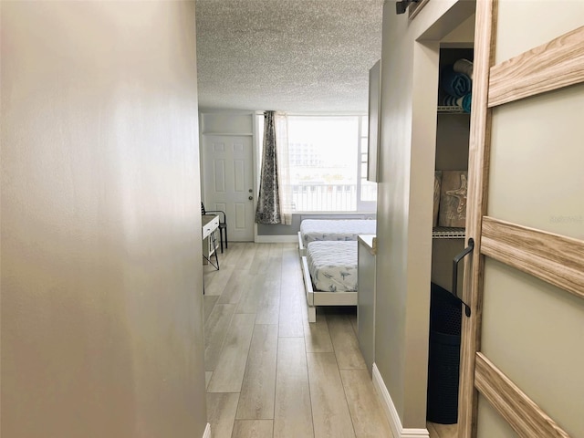 hallway with light hardwood / wood-style flooring and a textured ceiling