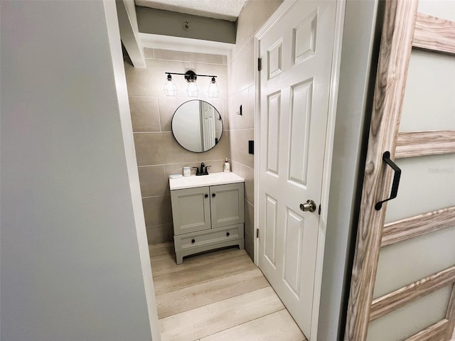 bathroom with tile walls, vanity, and hardwood / wood-style flooring