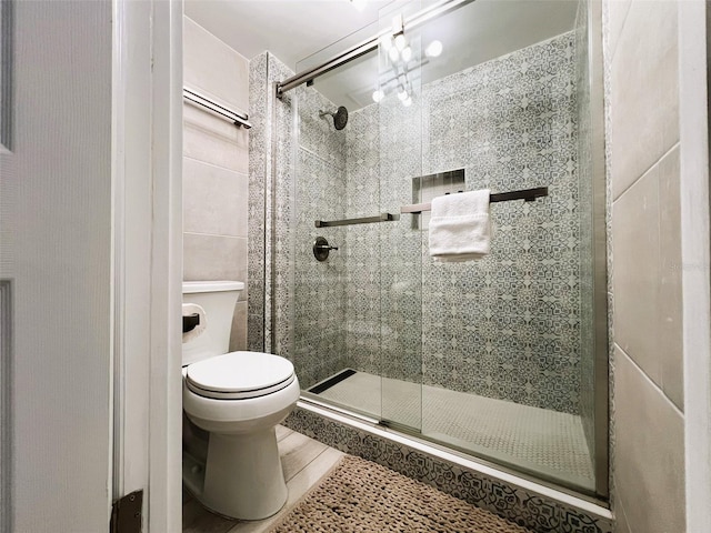 bathroom with tile patterned floors, a shower with shower door, and toilet