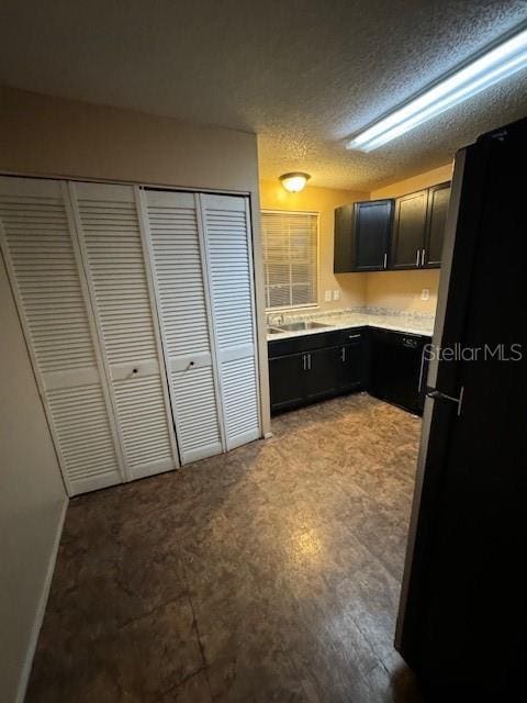 kitchen with light wood-type flooring, stainless steel fridge, a textured ceiling, and sink