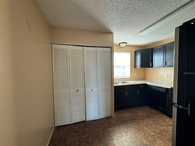 kitchen featuring fridge, black dishwasher, and a textured ceiling