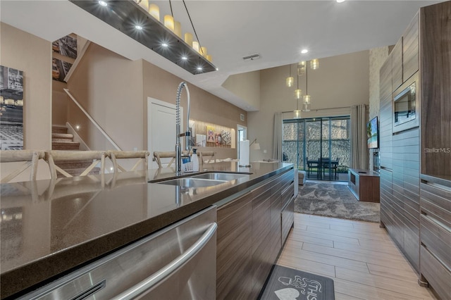 kitchen with appliances with stainless steel finishes, decorative light fixtures, sink, and dark stone counters