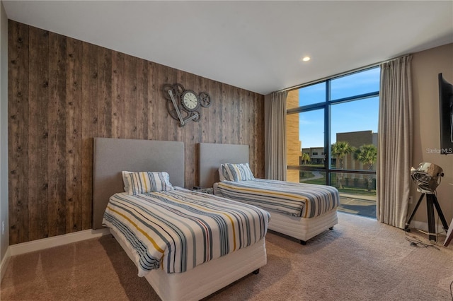 bedroom featuring carpet flooring, wooden walls, and a wall of windows