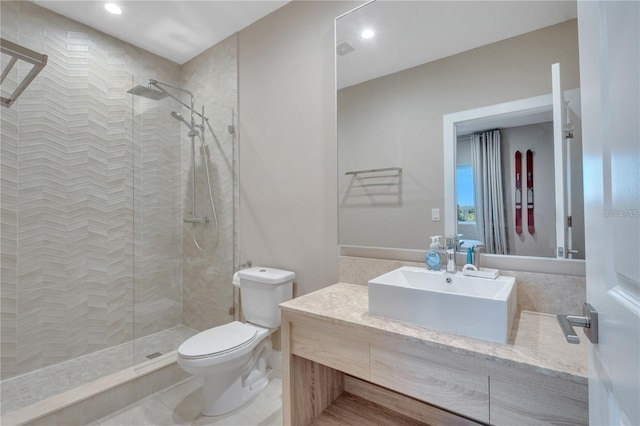 bathroom featuring vanity, toilet, and a tile shower