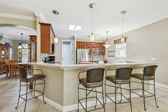 kitchen with stainless steel fridge, kitchen peninsula, crown molding, and light tile patterned floors