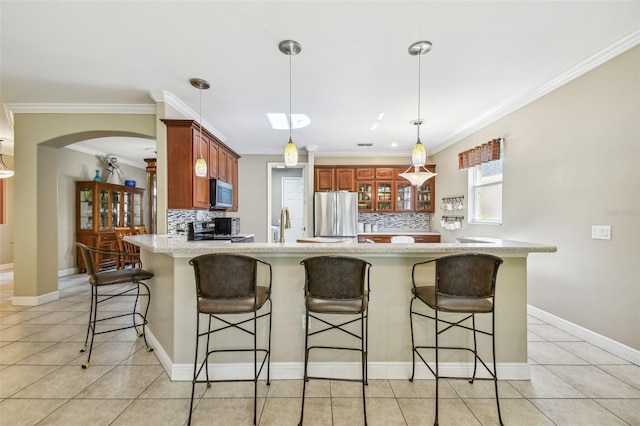 kitchen with decorative backsplash, kitchen peninsula, ornamental molding, a kitchen bar, and appliances with stainless steel finishes