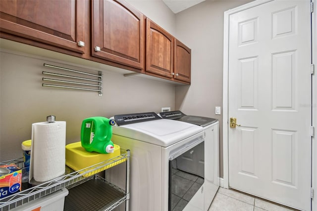 laundry room with light tile patterned flooring, washer and clothes dryer, and cabinets