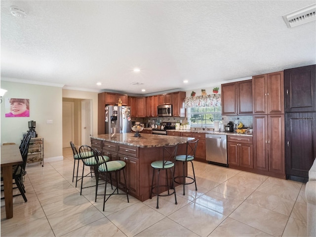 kitchen with decorative backsplash, a breakfast bar area, stainless steel appliances, dark stone countertops, and a center island