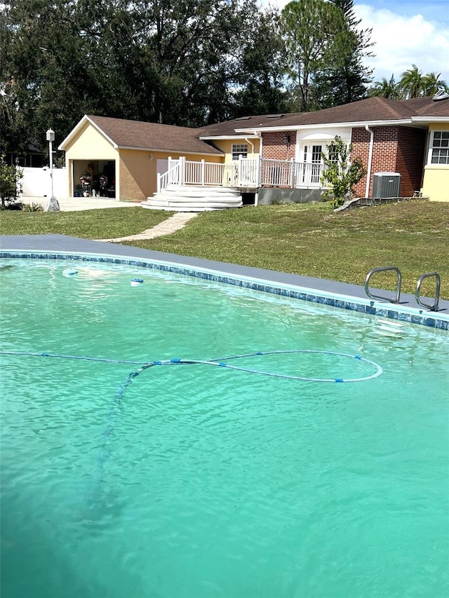 view of swimming pool featuring central AC and a lawn