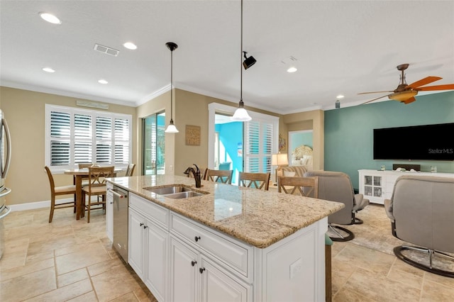 kitchen featuring a center island with sink, sink, white cabinets, and pendant lighting