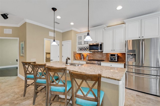 kitchen featuring white cabinetry, light stone countertops, stainless steel appliances, and a center island with sink